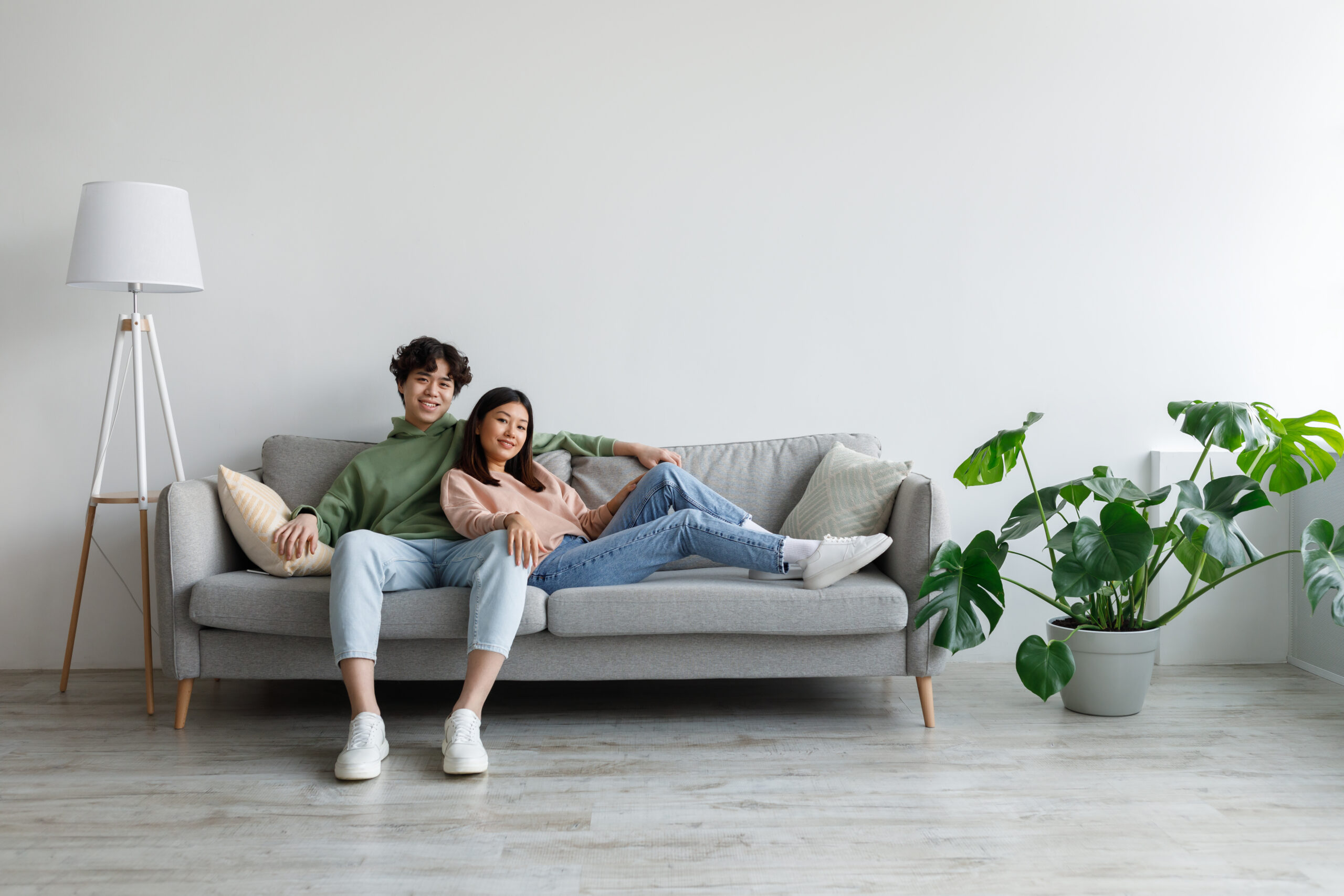 Affectionate young Asian couple cuddling on couch in living room,Expert HVAC Plumbing Electrical